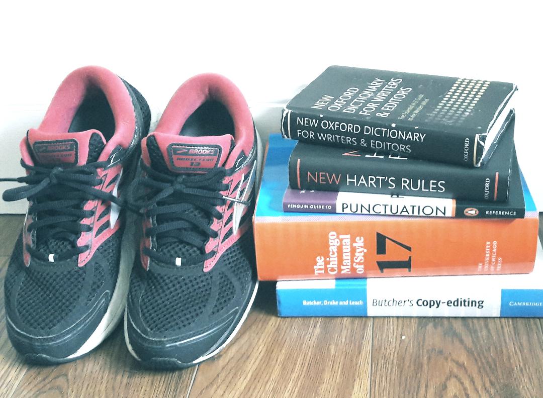Running shoes beside a pile of style guides, dictionaries, and other editorial books.