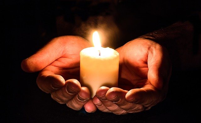 Hands in darkness holding a candle