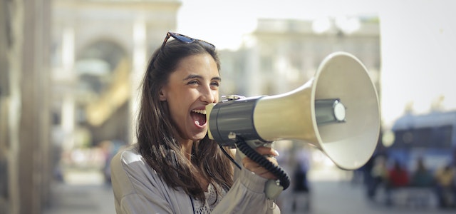 A smiling woman shouts into a megaphone