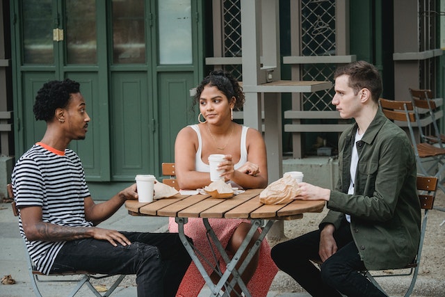 a group of three friends in conversation at a cafe table
