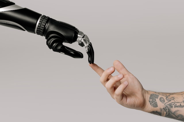a human hand touches a robot hand, mimicking Michelangelo